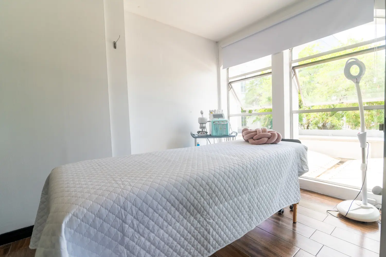 Cabina de tratamiento de Áurea Skin Clinic con ventanales y luz natural sobre la camilla